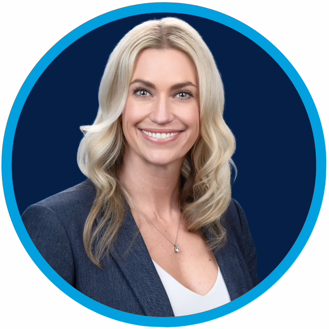 3 Professional headshot of a woman with long blonde hair, wearing a blue blazer and white top, smiling against a dark blue background with a circular blue border.