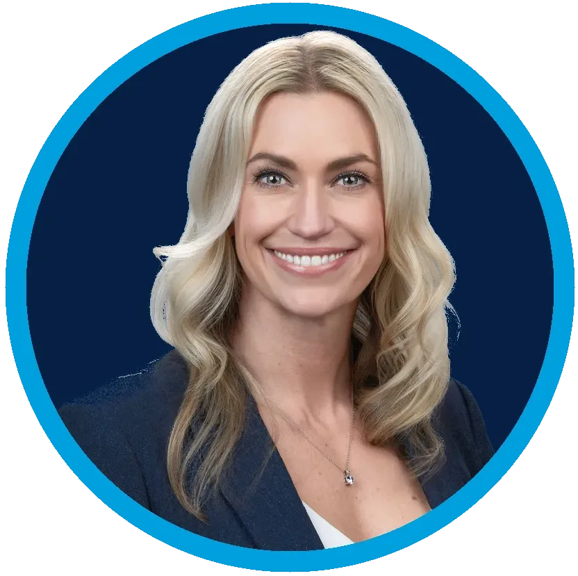 Professional headshot of a woman with long blonde hair, wearing a blue blazer and white top, smiling against a dark blue background with a circular blue border.